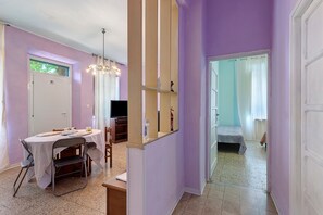 Ein Zimmer mit Esstisch, Stühlen, einem Fernseher und einem Spiegel.