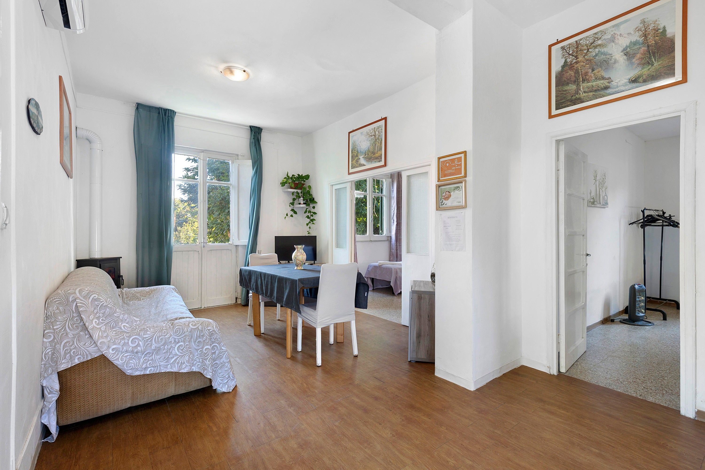 Quarto com cama, mesa de jantar com cadeiras, televisão e um quadro na parede.