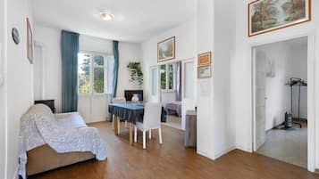 Quarto com cama, mesa de jantar com cadeiras, televisão e um quadro na parede.