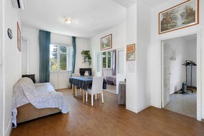 Una habitació amb un llit, una taula de dinar amb cadires, una televisió i un quadre a la paret.