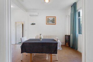 Zona de menjador amb taula preparada per a dues persones, un vas i un quadre al mur.