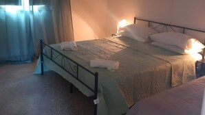 A single bed with a metal frame, a bedside table with a lamp, and a window with sheer curtains. - 'Rifugio Del Benessere' Apartment (Monte Compatri)