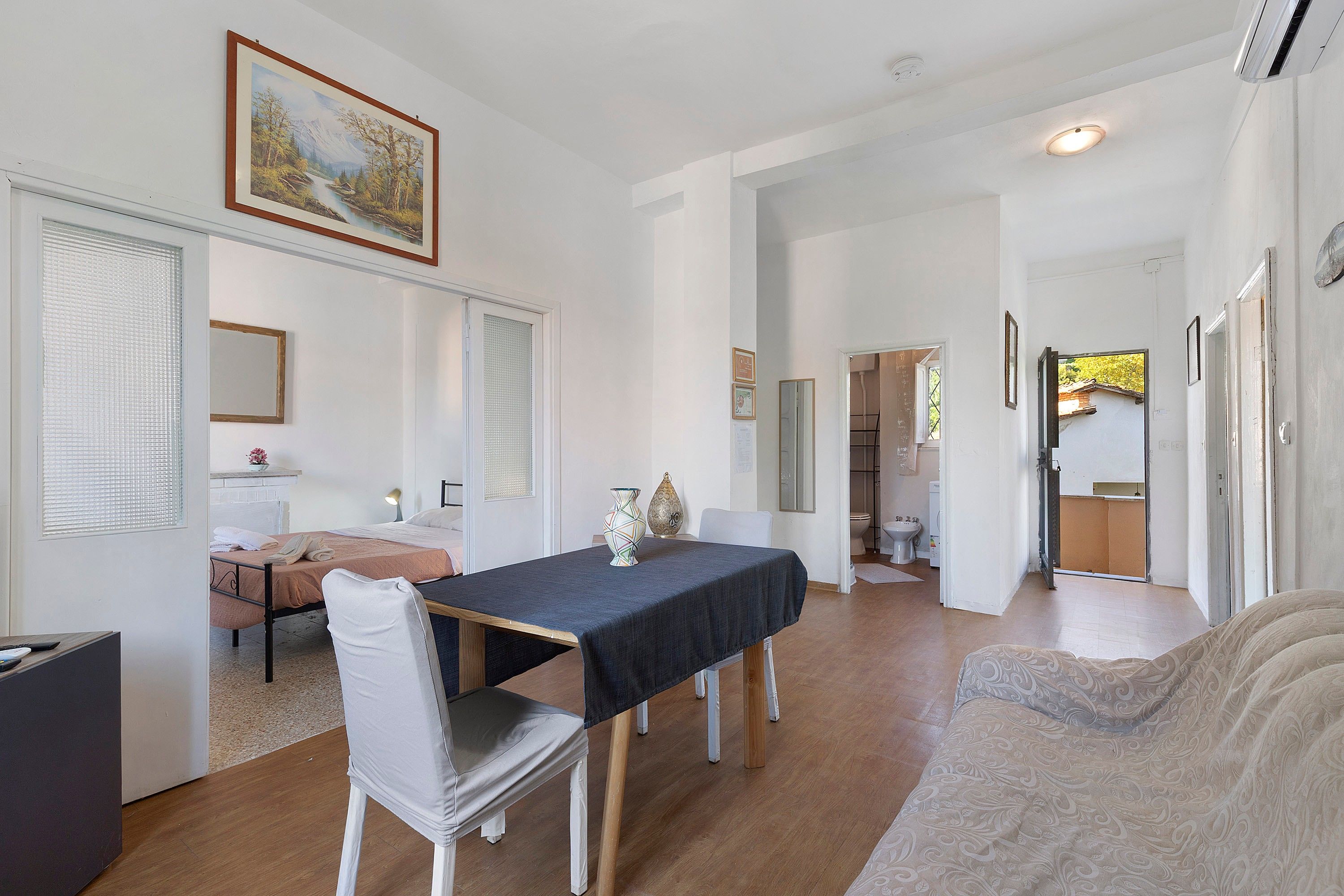 Ein Zimmer mit Esstisch, Stühlen, einer Couch und einem Bild an der Wand.