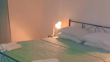 Ein Bett mit grüner Bettdecke, weißen Kissen und einer Nachttischlampe.