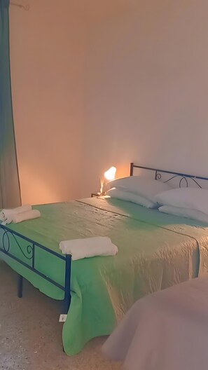 A bed with a green bedspread, white pillows, and a bedside lamp. - 'Rifugio Del Benessere' Apartment (Monte Compatri)
