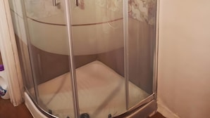 A glass-enclosed shower stall with a white tiled wall and a patterned tile design above. - 'Rifugio Del Benessere' Apartment (Monte Compatri)
