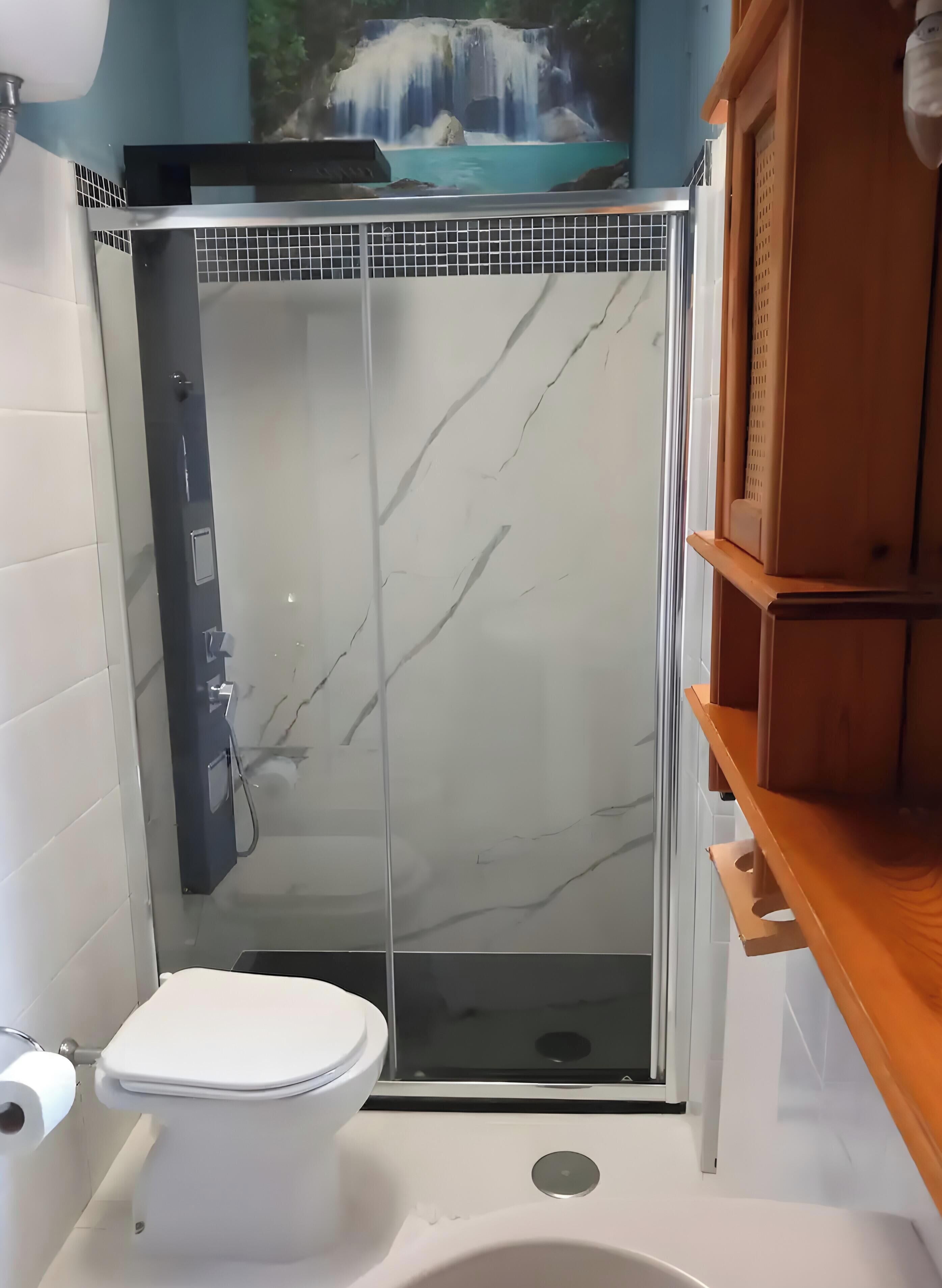 A bathroom with a toilet, a shower enclosure, and a sink.
