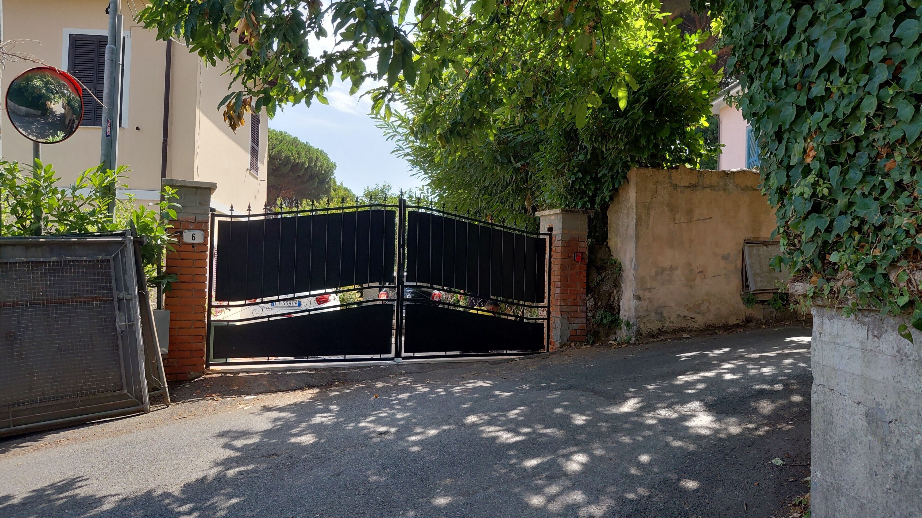 A gated entrance with a metal gate, a brick wall, and a number '6' sign.