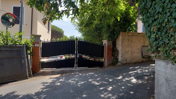 Une entrée fermée par un portail en métal, un mur de briques et une plaque portant le chiffre « 6 ».