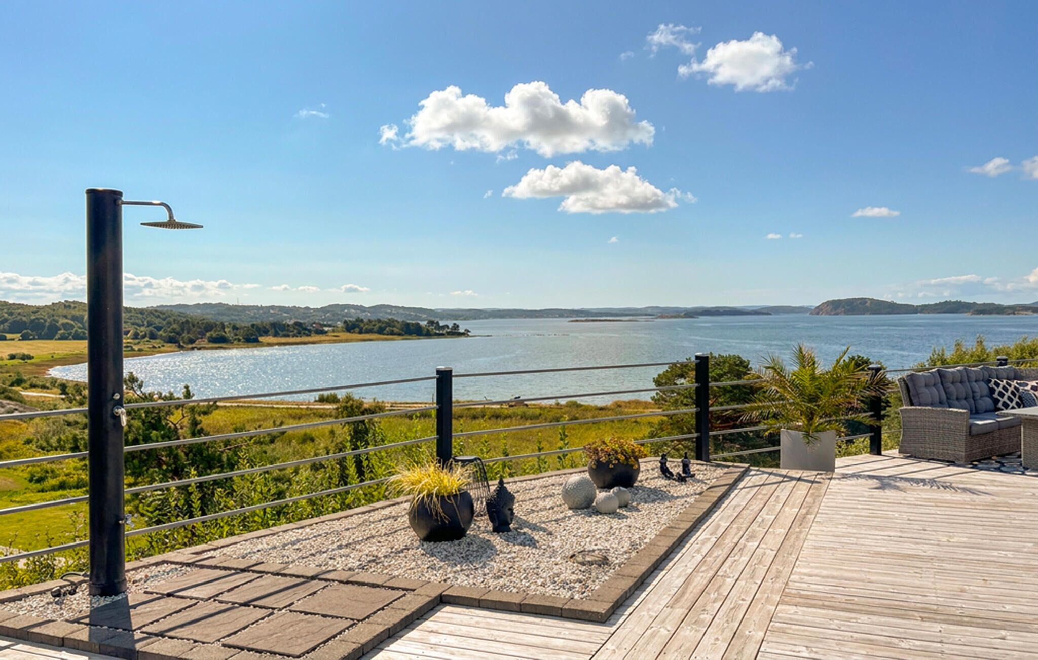 Une terrasse offrant une vue sur un lac, entourée de verdure et sous un ciel dégagé.