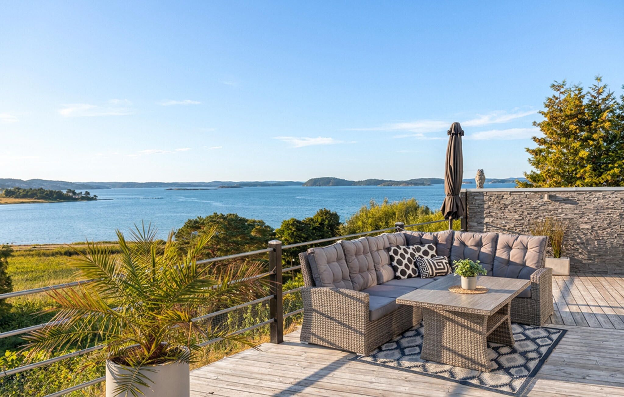 A deck with outdoor furniture overlooking a body of water.