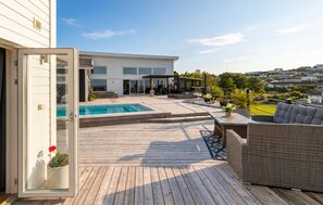 A wooden deck with a swimming pool, outdoor furniture, and a view of a modern house. - Gorgeous home in Uddevalla with private swimming pool, can be inside or outside (Uddevalla)
