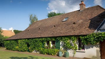Ett traditionellt hus med ett sluttande tak, murgrönebeklädda väggar och ett litet fönster.