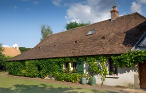 A traditional house with a sloped roof, ivy-covered walls, and a small window.