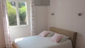 Ein Schlafzimmer mit einem Einzelbett, einem Fenster mit Vorhängen und einem Holzboden.