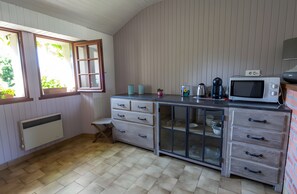 A compact kitchen with a window, a radiator, a microwave, and a coffee maker.