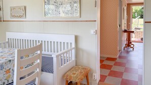 A room with a crib, a small stool, a table with a floral tablecloth, a wall-mounted picture, and a patterned floor. - Cozy home in Bestorp with WiFi (Bestorp)