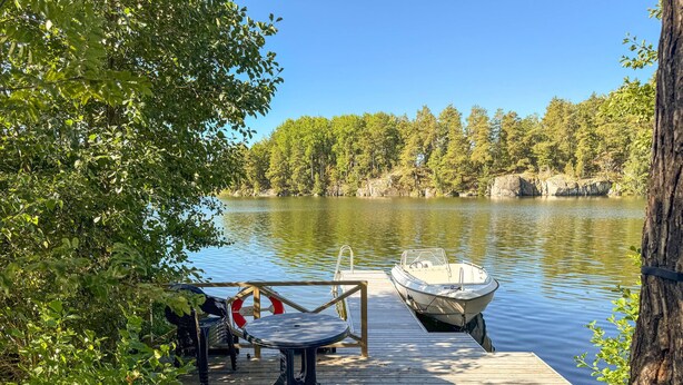 A wooden dock with a boat moored at the end, surrounded by trees and a calm lake. - Cozy home in Bestorp with WiFi (Bestorp)
