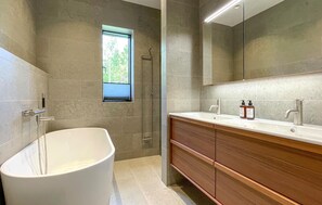 Une salle de bain moderne avec une baignoire sur pieds, une douche à l  ’italienne et un meuble-lavabo doté d’un grand miroir.