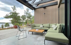 Un espace extérieur moderne, aménagé avec un canapé vert, une table basse en bois et une chaise en métal.