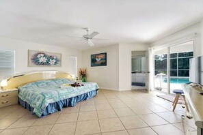 A bedroom with a bed, a ceiling fan, a painting, and a view of a pool through a glass door. - CCVS - Villa Allegra (Cape Coral)