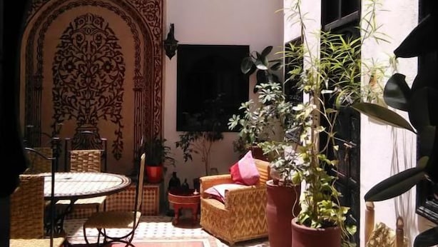 Een binnentuin met een eethoek, een bank en planten in potten.