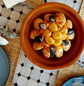 A terracotta bowl filled with dates and nuts on a tiled floor. - Riad Dar Zampa (Marrakech)