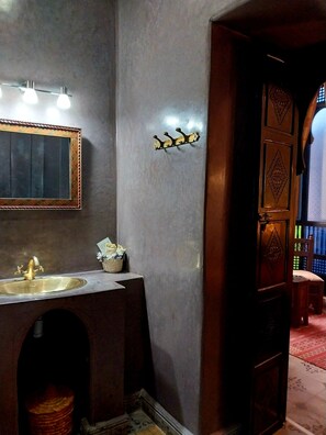 A bathroom with a sink, mirror, and wall-mounted lights. - Riad Dar Zampa (Marrakech)
