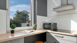 Una cocina moderna con horno empotrado, una ventana con vistas a árboles y dos taburetes.