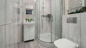 A modern bathroom with a glass-enclosed shower, a white sink, and a toilet. - Cozy Apartment with Bedroom | Smart TV and Washing Machine (Łódź)