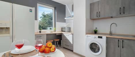 A modern kitchen with a built-in washing machine, a dining area with a table set for two, and a window providing a view of the outdoors.