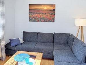 A living room with a grey sofa, a coffee table with a blue glass, and a painting of a field of red flowers. - Vacation home Albert by Interhome (Bad Staffelstein)