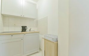 A kitchen with white cabinets, a coffee maker, and a dish rack on a wooden cabinet.