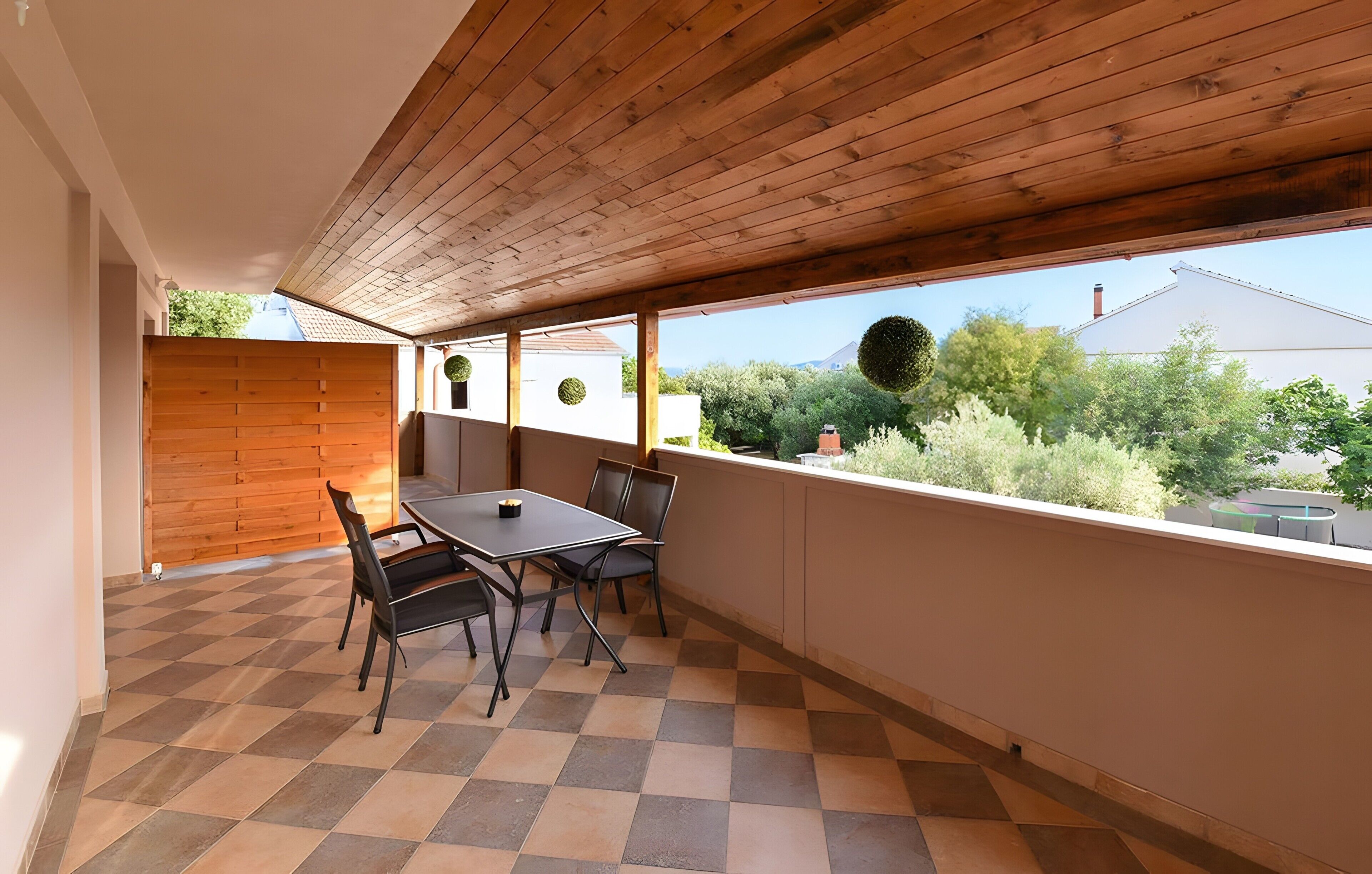 Een balkon met een geruite vloer, een tafel en stoelen.
