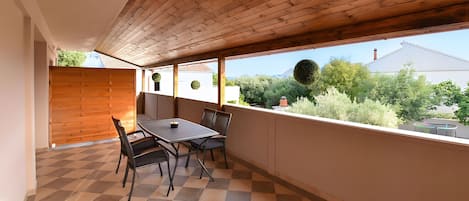 A balcony with a checkered floor, a table, and chairs.