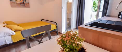 Ett modernt hotellrum med en säng, ett litet bord, en växt, en tv och utsikt över omgivningarna.