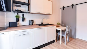 A modern kitchen with white cabinets, a black countertop, a sink, and a dining area with a table and chairs.