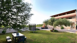 Un espace extérieur bien entretenu, comprenant un trampoline, une table avec des chaises et un bâtiment doté d’un toit rouge.