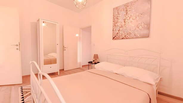 Un dormitorio con una cama, una mesita de noche, una lámpara, un espejo y una puerta.