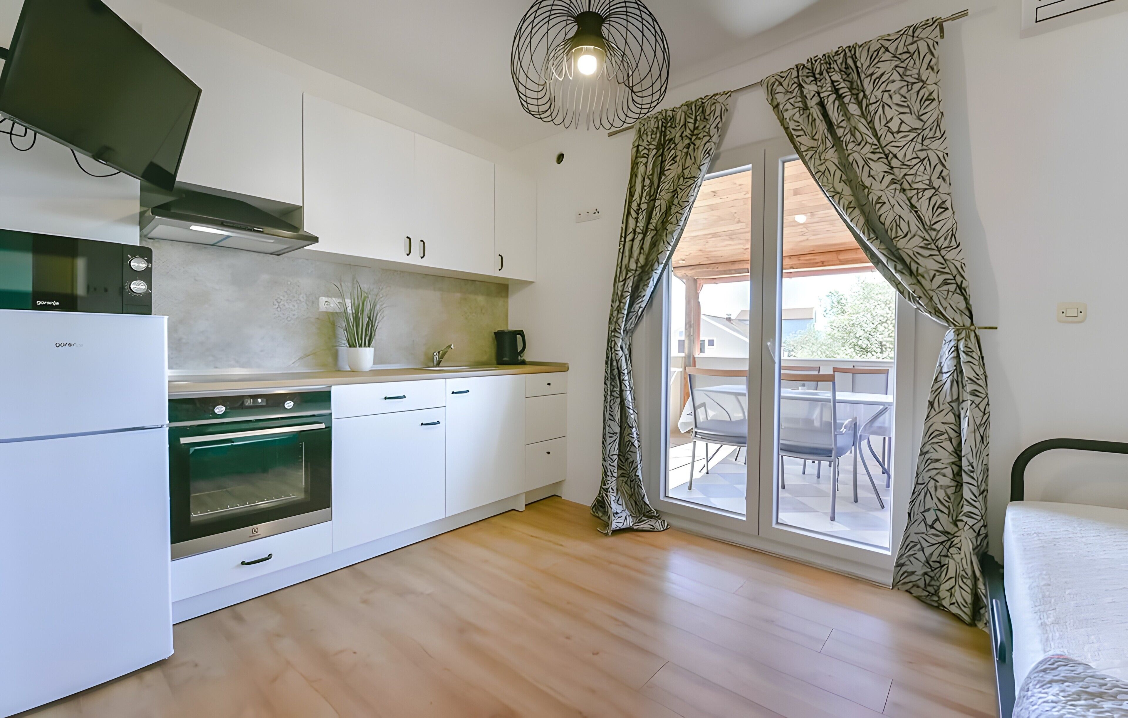 A modern kitchen with white cabinets, a built-in oven, and a dining area with a table and chairs.