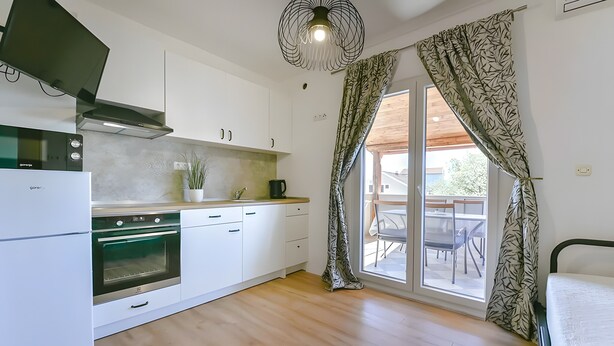 Uma cozinha moderna com armários brancos, forno embutido e área de jantar com mesa e cadeiras.