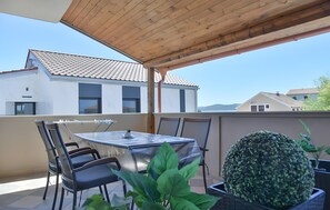 Eine Außenpatio mit Tisch und Stühlen, einem Blumentopf und Blick auf ein Gebäude mit Ziegeldach.