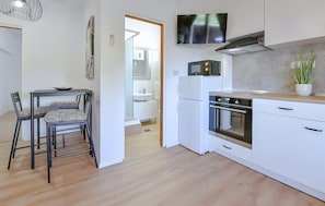 Una cucina moderna con mobili bianchi, forno integrato e microonde sul piano di lavoro.