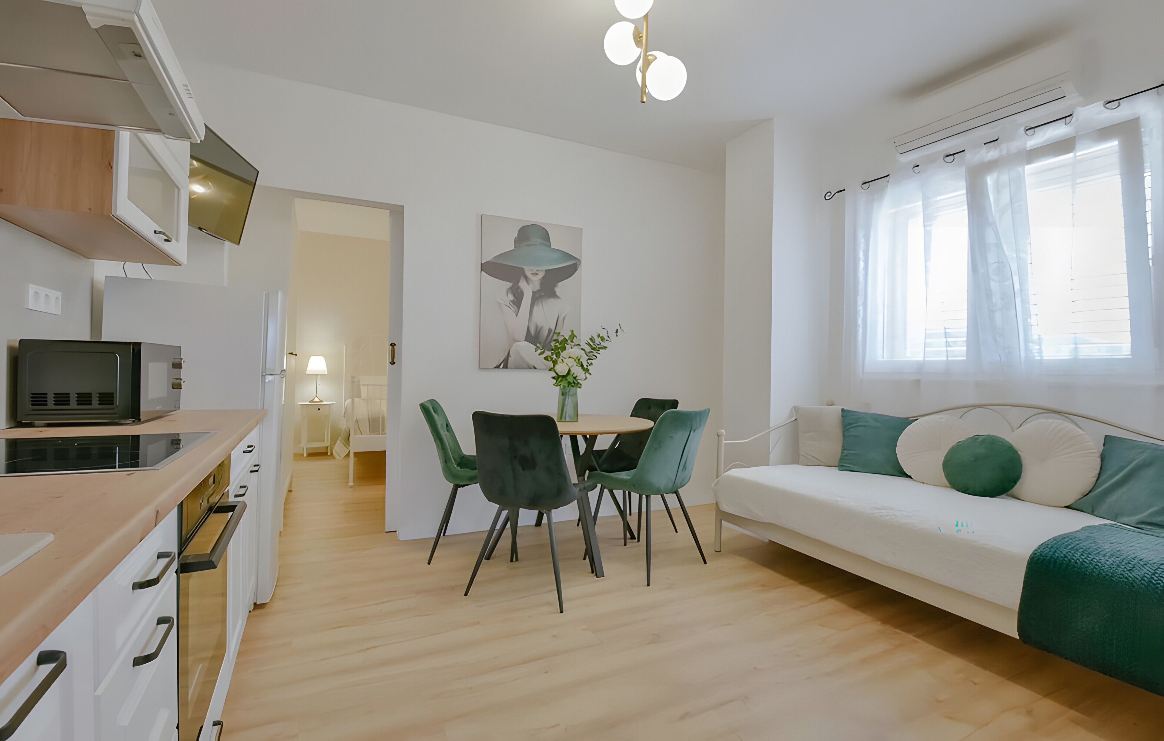 A modern living space with a dining area, a sofa, and a kitchen.