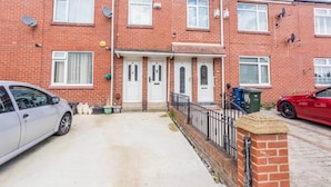 A two-story brick house with a front door, satellite dishes, and a car parked in the driveway. - The Geordie Getaway! (Newcastle upon Tyne)
