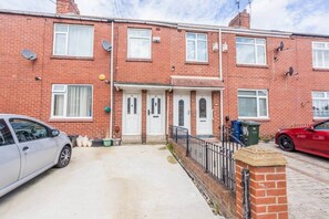 A two-story brick house with a front door, satellite dishes, and a car parked in the driveway. - The Geordie Getaway! (Newcastle upon Tyne)