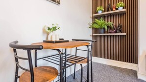 A corner of a room with a wooden table and chairs, a wall-mounted shelf with plants, and a painting. - The Geordie Getaway! (Newcastle upon Tyne)