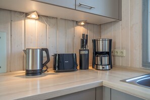 A kitchen with a coffee maker, a kettle, and a toaster on the counter. - Holiday Home '55 Typ Eisvogel' with Private Terrace, Private Garden and Wi-Fi (Rechlin)