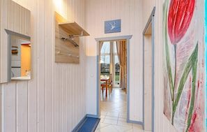 A hallway with a wooden door leading to a dining area, a wall-mounted light fixture, and a door with a glass panel.