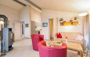A modern living room with a fireplace, red chairs, a sofa, and a wooden coffee table.
